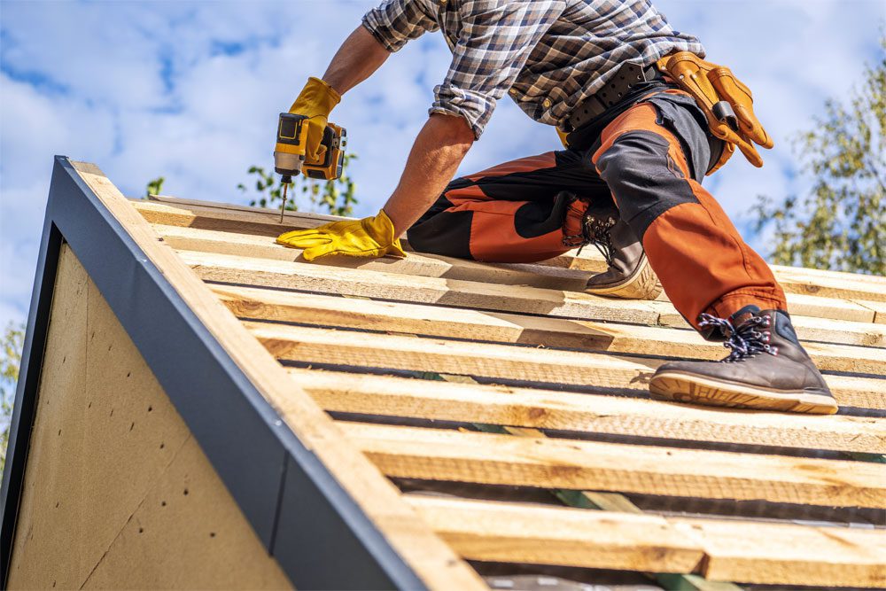 Gilbert-Blog-Featured-Image-Reconstruction-Cost-vs-Replacement-Value Image of a worker repairing the roof of a house