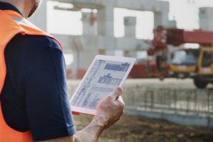 Photo of a construction worker looking at a tablet device on a construction site