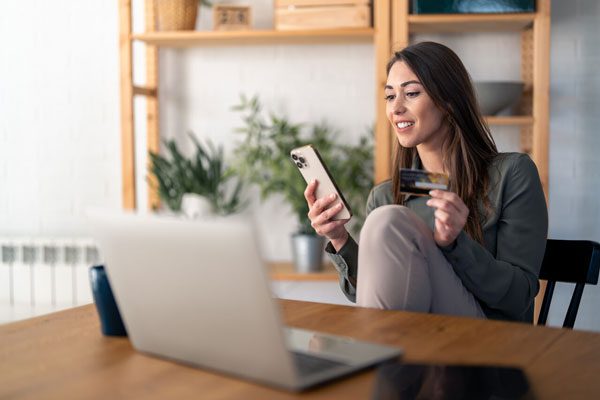 Photo of a woman entering credit card details into her smartphone and laptop